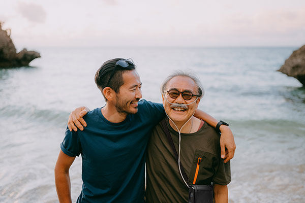 An Asian father with COPD and son at the beach and the father has an Inogen One G4 system