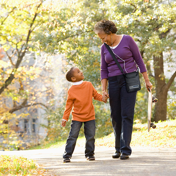 African American Grandmother with COPD using the Inogen Rove 6 portable oxygen concentrator playing with her grandson in the park.